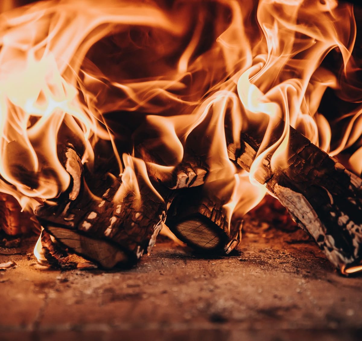 Close-up of burning logs with tall flames on a stone hearth