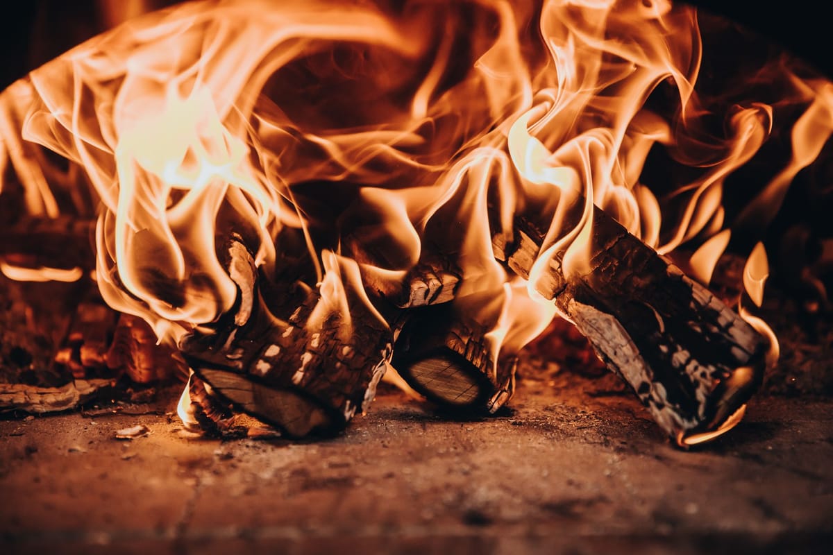 Close-up of burning logs with tall flames on a stone hearth