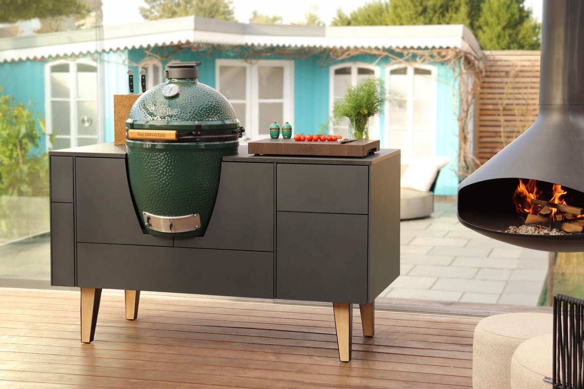 FREILUFT island with anthracite fronts, oak legs and a built-in Big Green Egg on a wooden deck, hanging fireplace