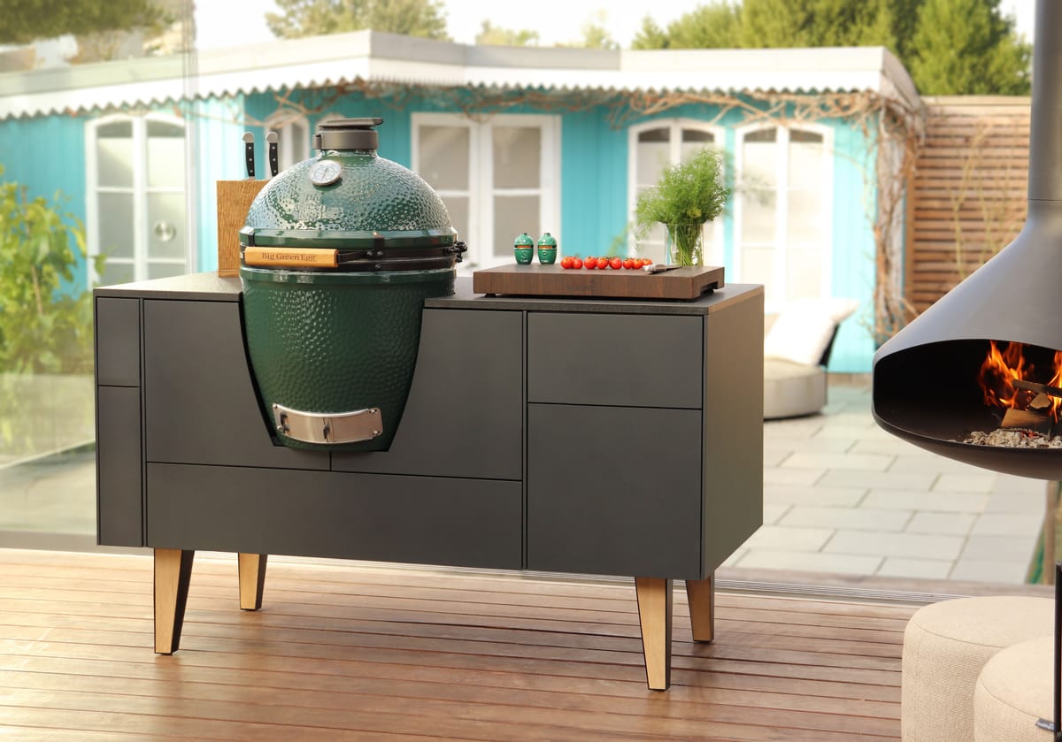 FREILUFT island with anthracite fronts, oak legs and a built-in Big Green Egg on a wooden deck, hanging fireplace