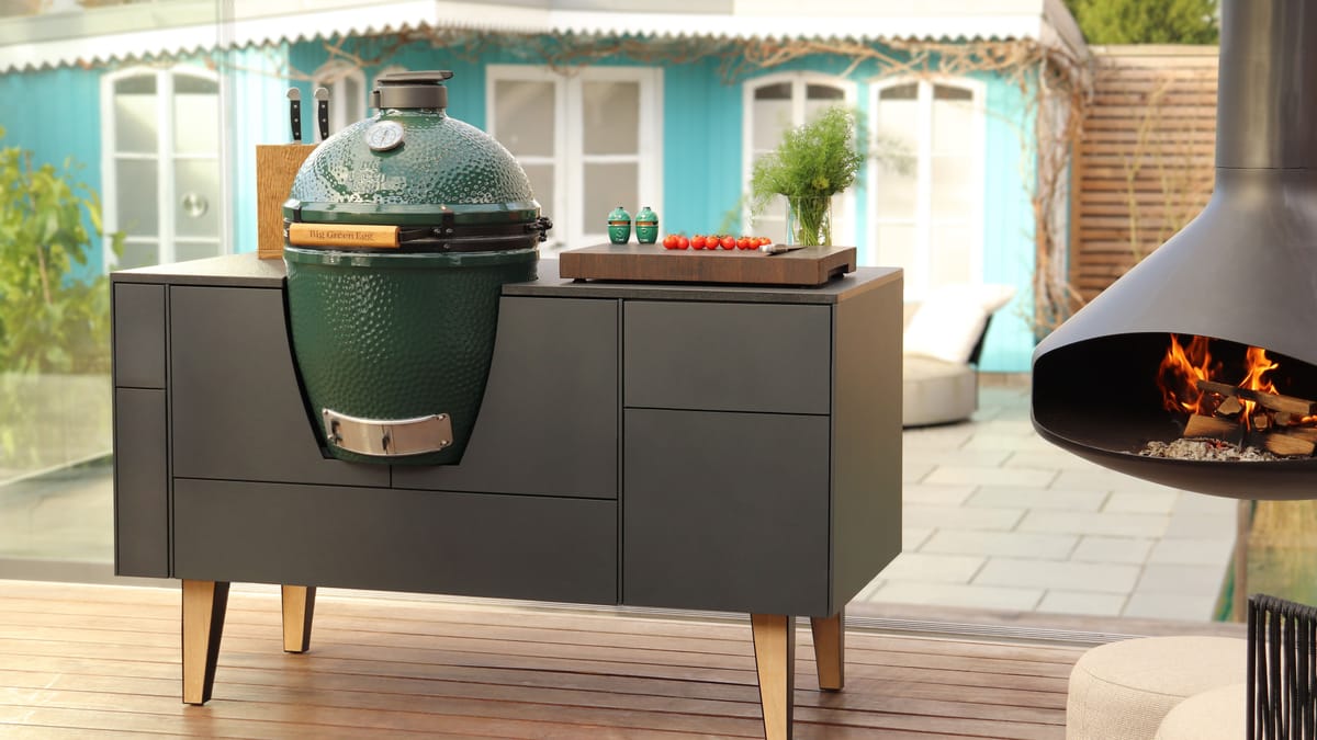 FREILUFT island with anthracite fronts, oak legs and a built-in Big Green Egg on a wooden deck, hanging fireplace